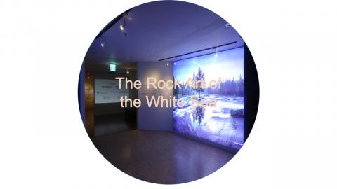 Button for the Rock Art of the White Sea project showing an image of an archaeological site projected on a screen at the museum exhibition in South Korea